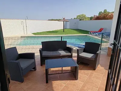a patio with chairs and a table and a swimming pool at Lakuarta in Hozanejos