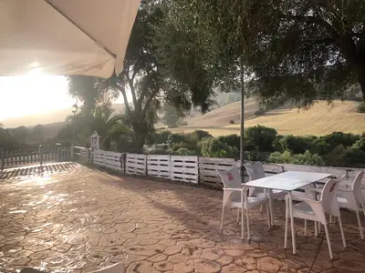 a table with white chairs and an umbrella on a patio at Grupo El Duende A&G in San Jose del Valle