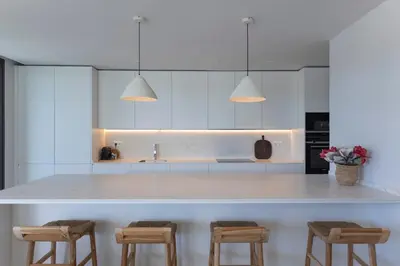 a kitchen with white cabinets and a large island with stools at GINVA - Luxury Beachfront Apartment in El Puerto de Santa María