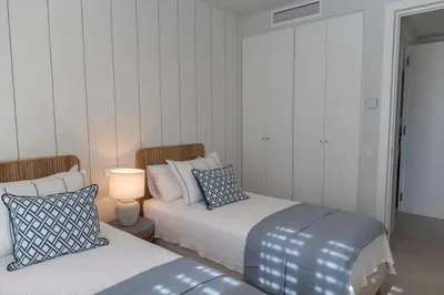 two beds in a room with a lamp and a bed sidx sidx sidx at GINVA - Luxury Beachfront Apartment in El Puerto de Santa María
