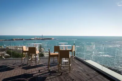 a balcony with chairs and a table on a roof at Parador de Cádiz in Cádiz