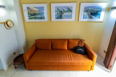 an orange couch in a room with pictures on the wall at SH Brisa de la Viña. Cerca de la Playa. AC, WIFi in Cádiz