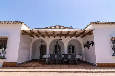 a patio of a white building with tables and chairs at Parisito beach in Chiclana de la Frontera