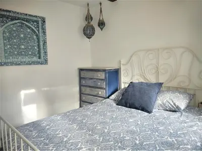 a bedroom with a bed with a blue pillow and a dresser at Parisito beach in Chiclana de la Frontera