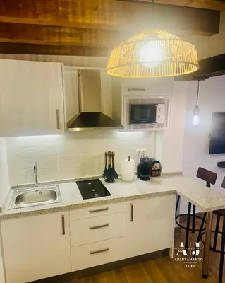 a kitchen with white cabinets and a sink and a lamp at Apartamento con Entreplanta Alegría de Jerez in Jerez de la Frontera