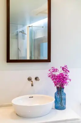 a bathroom sink with a vase of flowers and a mirror at Parador de Arcos de la Frontera in Arcos de la Frontera
