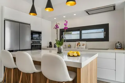 a kitchen with a table and white chairs at Villa Paradisus Golf & Wellnes in Cádiz