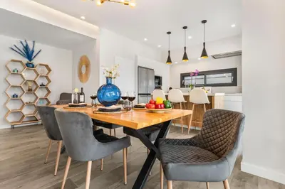 a dining room and kitchen with a wooden table and chairs at Villa Paradisus Golf & Wellnes in Cádiz