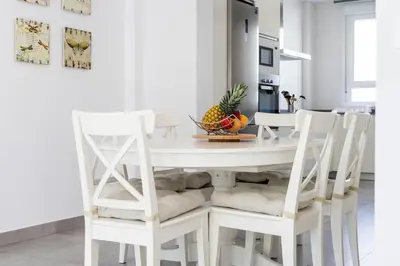 a white dining room table with white chairs and a bowl of fruit at Conil Seaside Hideaway in Conil de la Frontera