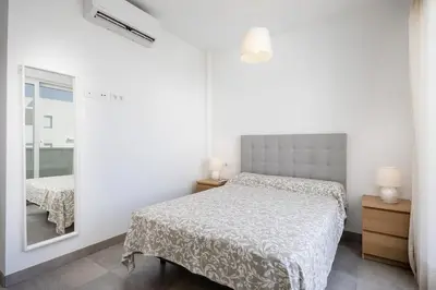 a white bedroom with a bed and a mirror at Conil Seaside Hideaway in Conil de la Frontera