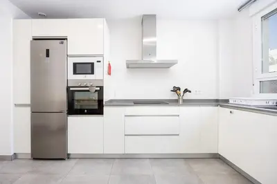 a kitchen with white cabinets and a stainless steel refrigerator at Conil Seaside Hideaway in Conil de la Frontera