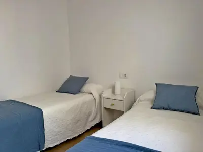 two twin beds in a room with white walls and blue pillows at Apartamento Brisa Candor - Ole Solutions in Rota