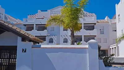 a white fence with a palm tree in front of a building at Apartamento Brisa Candor - Ole Solutions in Rota