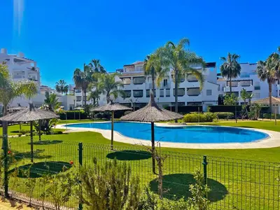 a large swimming pool with umbrellas and a building at Apartamento Brisa Candor - Ole Solutions in Rota