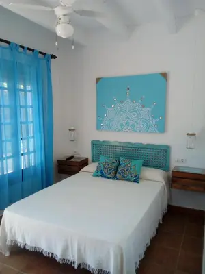 a bedroom with a large white bed with blue curtains at Alojamiento Rural 