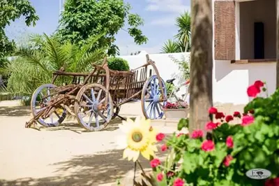 a wooden horse drawn carriage in a yard with flowers at Alojamiento Rural 