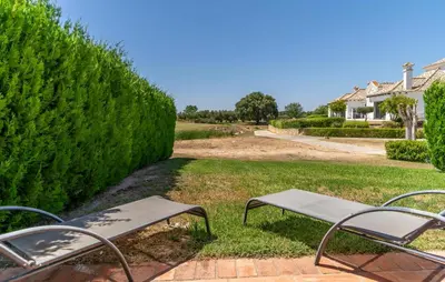 a bench sitting in the grass next to a hedge at Pet Friendly Home In Arcos De La Frontera in Arcos de la Frontera