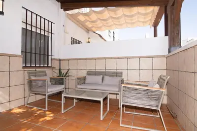 a patio with chairs and a couch and a table at Stylish 3-Bedrooms Getaway with Terrace & Pool in Chiclana de la Frontera