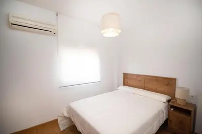 a white bedroom with a bed and a window at Stylish 3-Bedrooms Getaway with Terrace & Pool in Chiclana de la Frontera