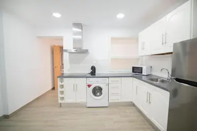 a white kitchen with a washing machine in it at Stylish 3-Bedrooms Getaway with Terrace & Pool in Chiclana de la Frontera