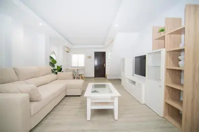 a white living room with a couch and a table at Stylish 3-Bedrooms Getaway with Terrace & Pool in Chiclana de la Frontera