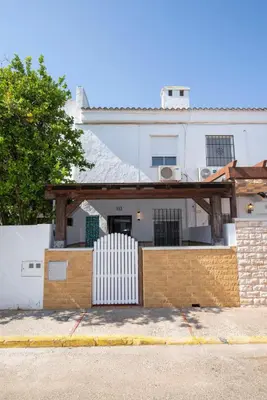 a white house with a fence in front of it at Stylish 3-Bedrooms Getaway with Terrace & Pool in Chiclana de la Frontera