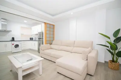 a white living room with a couch and a table at Stylish 3-Bedrooms Getaway with Terrace & Pool in Chiclana de la Frontera