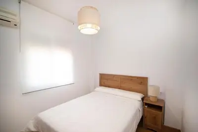 a white bedroom with a bed and a window at Stylish 3-Bedrooms Getaway with Terrace & Pool in Chiclana de la Frontera