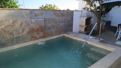a pool of water in a backyard with a fireplace at Villa Juana in Conil de la Frontera
