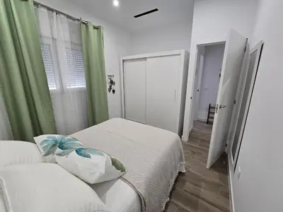 a bedroom with two beds and a window with green curtains at Piso El IDEAL in Lebrija