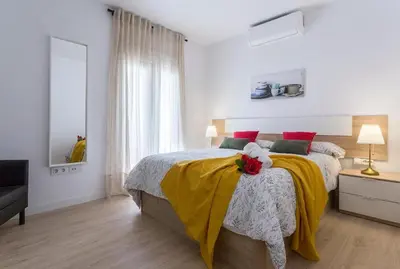 a white bedroom with a bed with a yellow blanket at Allo Apartments Morenos VI in Jerez de la Frontera