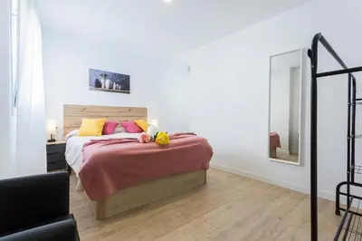 a bedroom with a bed with pink and yellow pillows at Allo Apartments Morenos VI in Jerez de la Frontera