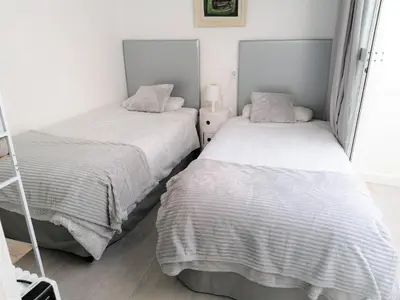 two beds in a small room with white walls at Apartamento junto a PLAYA LAS REDES-VISTAHERMOSA, CADIZ in El Puerto de Santa María