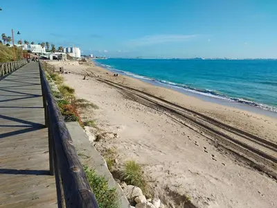 a beach with a wooden boardwalk next to the ocean at Apartamento junto a PLAYA LAS REDES-VISTAHERMOSA, CADIZ in El Puerto de Santa María