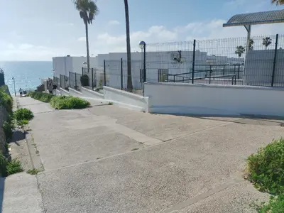 a sidewalk next to the ocean with a fence at Apartamento junto a PLAYA LAS REDES-VISTAHERMOSA, CADIZ in El Puerto de Santa María
