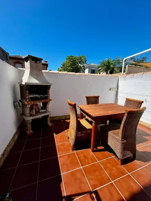a patio with a wooden table and chairs and a fireplace at Barrosa Living in Chiclana de la Frontera