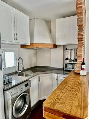 a kitchen with white cabinets and a wooden counter top at Barrosa Living in Chiclana de la Frontera