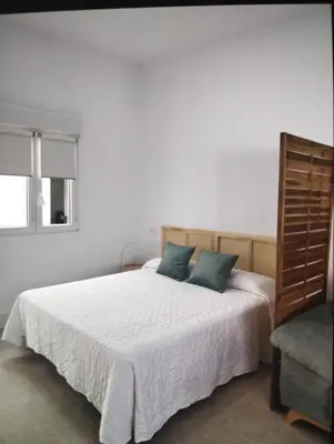 a bedroom with a white bed with two blue pillows at Estudio Álvaro in Cádiz
