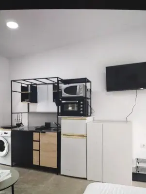 a room with a kitchen with a microwave and a tv at Estudio Álvaro in Cádiz