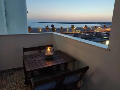 a table with a candle on a balcony with a view of the ocean at Apartamento Relax junto al Mar in El Puerto de Santa María