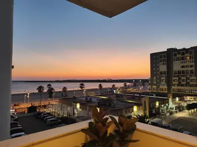 a view of the beach at sunset from the balcony of a hotel at Apartamento Relax junto al Mar in El Puerto de Santa María