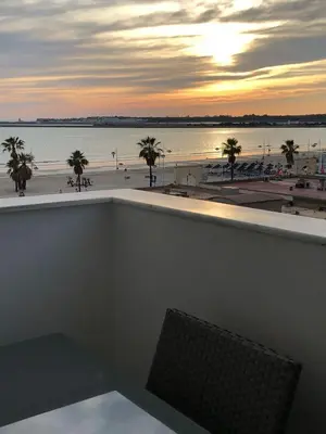 a view of the beach at sunset from a balcony at Apartamento Relax junto al Mar in El Puerto de Santa María