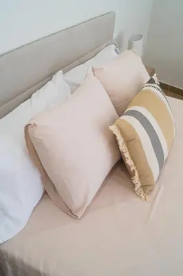 a bed with three pillows on top of it at Alojamientos Dunas del Alba in Chipiona