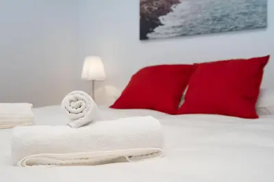 a pile of towels on a bed with red pillows at CDZ - Santiago Terry in Cádiz
