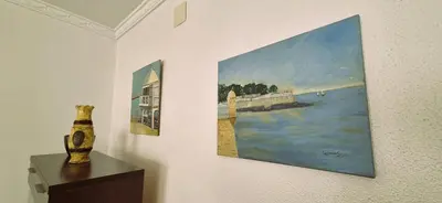 a wall with two paintings and a vase on a table at Torre 49 in Cádiz