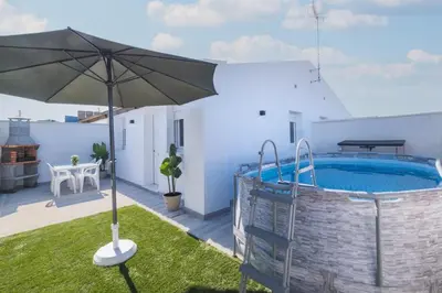 a patio with an umbrella and a swimming pool at Villa Kaki in Conil de la Frontera