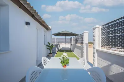 a table and chairs on a balcony with an umbrella at Villa Kaki in Conil de la Frontera
