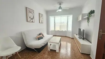 a living room with a white couch and a tv at Camaron Beach House By Sanlúcar Housing in Chipiona