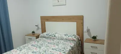 a bedroom with a bed with a floral bedspread and two night stands at Chalet casa la adelfa in Chiclana de la Frontera