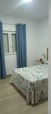 a bedroom with a bed and blue curtains at Chalet casa la adelfa in Chiclana de la Frontera
